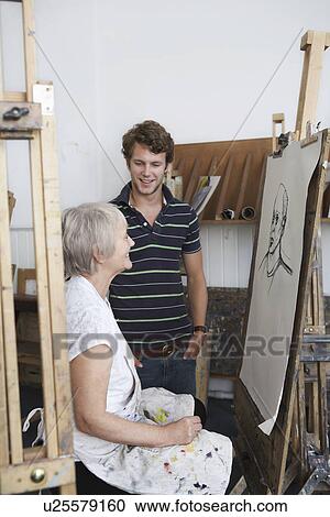 Artist drawing portrait in studio, young man looking on View Large Photo Image Stock Image - Artist drawing portrait in studio, young man looking on. Fotosearch