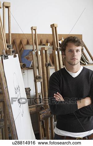 Stock Photograph - Artist standing by charcoal portrait in studio. Fotosearch