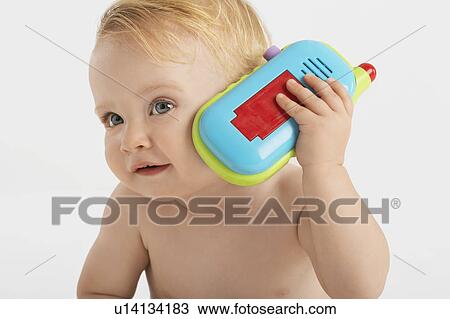 Stock Image - Baby Listening to Toy telephone. Fotosearch