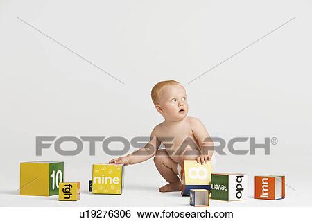 Stock Photograph - Baby Picking Up Blocks. Fotosearch
