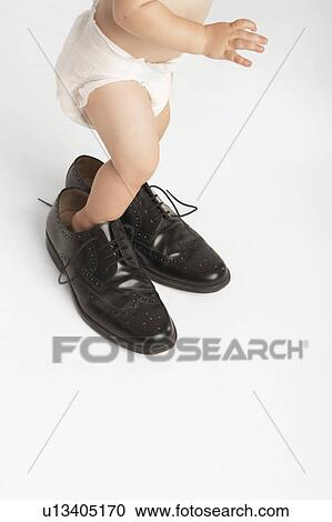 Baby Standing in Man's Shoes View Large Photo Image Stock Image - Baby Standing in Man's Shoes. Fotosearch