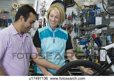 Stock Photograph - Bike shop assistant helps female cyclist. Fotosearch
