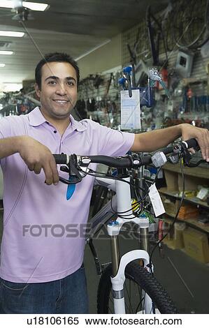 Stock Photography - Bike shop assistant stands holding new bike. Fotosearch