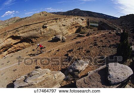 Stock Photo - Biker riding on mountain trail. Fotosearch