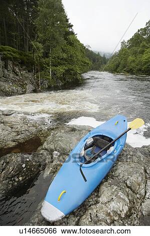 Stock Photograph - Blue kayak by river. Fotosearch