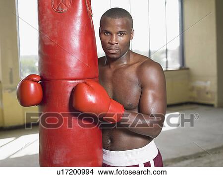 Picture - Boxer holding punching bag, portrait. Fotosearch
