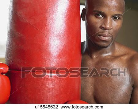 Stock Image - Boxer holding punching bag, portrait, close-up. Fotosearch
