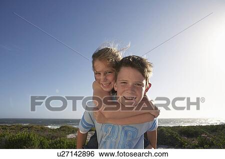 Boy giving girl piggyback in front of ocean, half length View Large Photo Image Stock Photograph - Boy giving girl piggyback in front of ocean, half length. Fotosearch