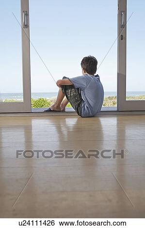 Boy sitting on floor in doorway looking at view View Large Photo Image Stock Photograph - Boy sitting on floor in doorway looking at view. Fotosearch