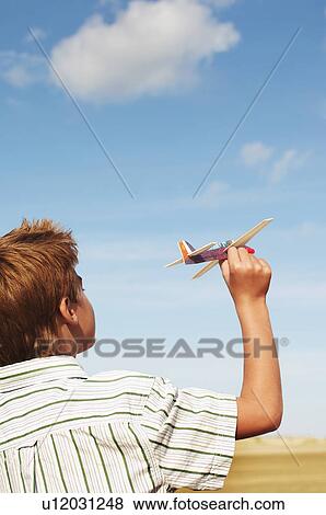 Stock Photo - Boy standing on beach Flying Toy Airplane, back view. Fotosearch