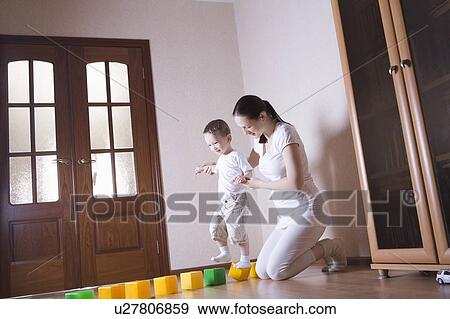 Boy walks along building blocks with help from his mother View Large Photo Image Stock Photo - Boy walks along building blocks with help from his mother. Fotosearch