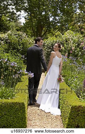 Bride and groom walking in garden, back view View Large Photo Image Stock Photograph - Bride and groom walking in garden, back view. Fotosearch