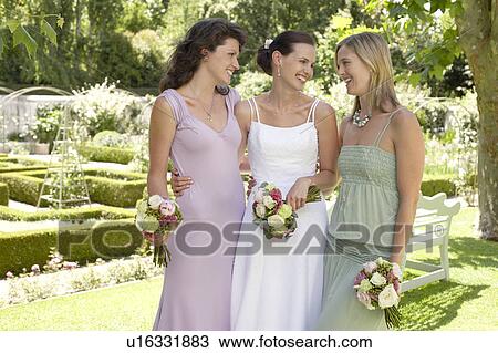 Bride with two women in garden, holding bouquets, smiling, portrait View Large Photo Image Stock Image - Bride with two women in garden, holding bouquets, smiling, portrait. Fotosearch