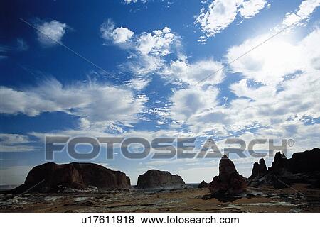 Stock Photo - Bright Clouds over Rugged Landscape. Fotosearch