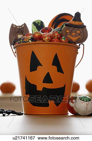 Stock Photo - Bucket with Jack O'lantern face filled with sweets in studio. Fotosearch