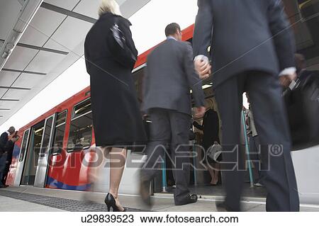 Stock Image - Business Commuters Getting on Train, motion blur, low angle view. Fotosearch