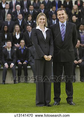 Business couple standing in front of business people sitting on tribune, portrait View Large Photo Image Stock Image - Business couple standing in front of business people sitting on tribune, portrait. Fotosearch