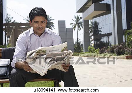 Stock Image - Business man carrying coffee next to business woman using mobile phone on city street. Fotosearch