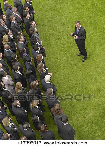 Business man facing large group of business people in formation, elevated view View Large Photo Image Stock Image - Business man facing large group of business people in formation, elevated view. Fotosearch