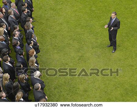 Business man facing large group of business people in formation, elevated view View Large Photo Image Stock Image - Business man facing large group of business people in formation, elevated view. Fotosearch