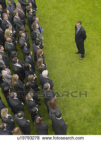 Business man facing large group of business people in formation, elevated view View Large Photo Image Stock Photo - Business man facing large group of business people in formation, elevated view. Fotosearch