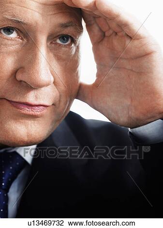 Stock Image - Business man holding hand up to face, close up. Fotosearch