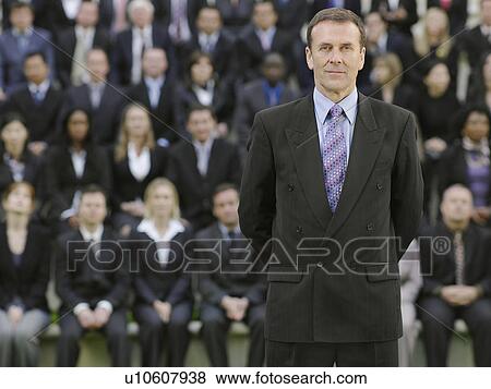 Business man standing in front of business people sitting on tribune, portrait View Large Photo Image Stock Photo - Business man standing in front of business people sitting on tribune, portrait. Fotosearch