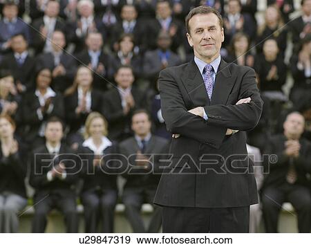 Business man standing in front of business people sitting on tribune, portrait View Large Photo Image Stock Photo - Business man standing in front of business people sitting on tribune, portrait. Fotosearch