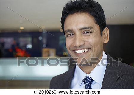 Stock Image - Business man standing in hotel lobby, portrait, close up. Fotosearch
