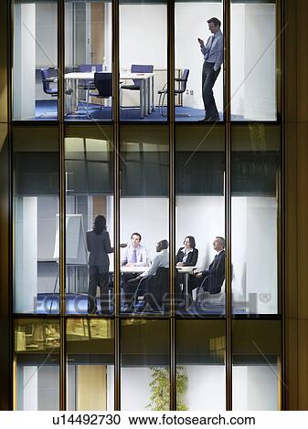 Business man text messaging on floor above group of business people at office meeting, view from building exterior View Large Photo Image Stock Image - Business man text messaging on floor above group of business people at office meeting, view from building exterior. Fotosearch