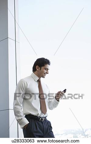 Business man using cell phone, smiling View Large Photo Image Stock Image - Business man using cell phone, smiling. Fotosearch