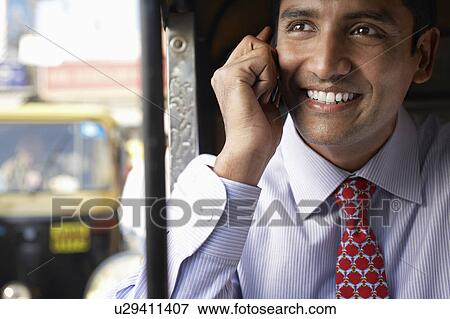 Stock Photo - Business man using cell phone, smiling. Fotosearch