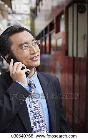 Stock Photo - Business man using mobile phone on street. Fotosearch