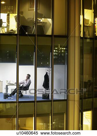 Business man working at desk in office, view from building exterior View Large Photo Image Stock Photography - Business man working at desk in office, view from building exterior. Fotosearch