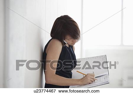 Stock Photo - Business woman on making notes in empty warehouse. Fotosearch