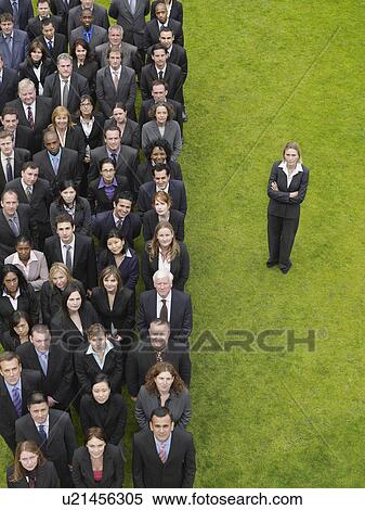 Stock Photography - Business woman standing next to large group of business people in formation, elevated view, portrait. Fotosearch