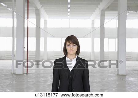 Stock Photo - Business woman stands in empty warehouse. Fotosearch