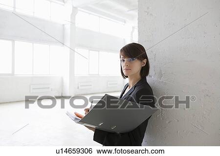 Stock Photograph - Business woman with file in empty warehouse. Fotosearch