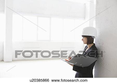 Stock Photograph - Business woman with file in empty warehouse. Fotosearch