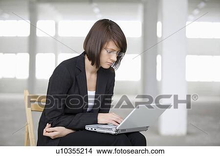 Business woman works on laptop in empty warehouse View Large Photo Image Picture - Business woman works on laptop in empty warehouse. Fotosearch