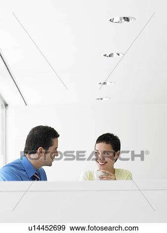 Stock Photo - Businessman and businesswoman having coffee indoors. Fotosearch