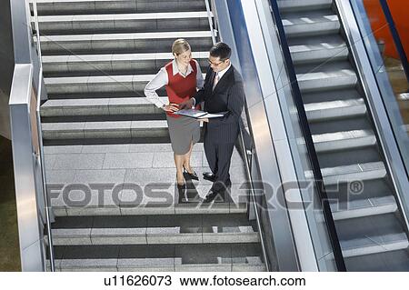 Businessman and businesswoman conversing on stairs, elevated view View Large Photo Image Stock Image - Businessman and businesswoman conversing on stairs, elevated view. Fotosearch