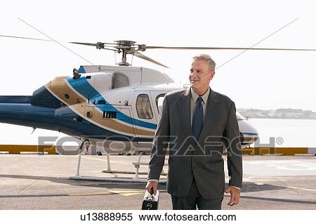 Stock Photography - Businessman arriving on helicopter pad. Fotosearch