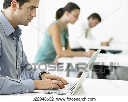 Stock Image - Businessman at table using laptop, close up. Fotosearch