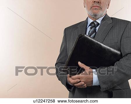 Stock Photo - Businessman Holding Leather Binder, half length, cropped. Fotosearch