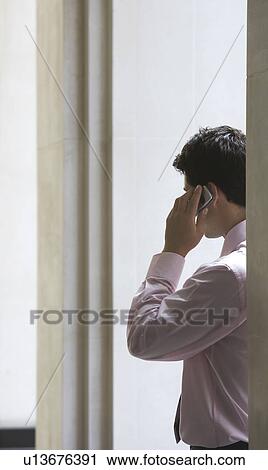 Businessman in archway talking on cell phone View Large Photo Image Stock Image - Businessman in archway talking on cell phone. Fotosearch