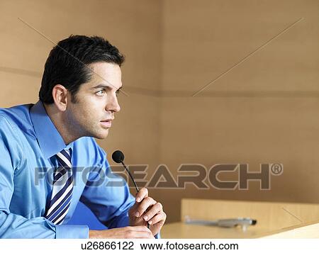 Stock Image - Businessman in conference room talking into microphone. Fotosearch