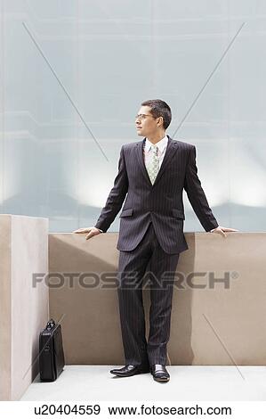 Stock Photo - Businessman leaning on wall, portrait. Fotosearch