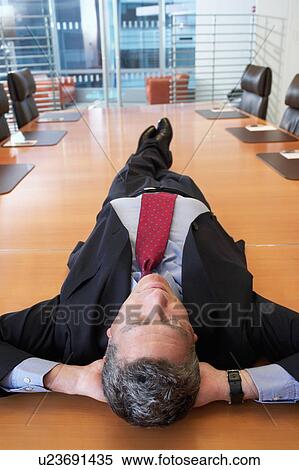 Businessman lying on conference table View Large Photo Image Stock Photography - Businessman lying on conference table. Fotosearch