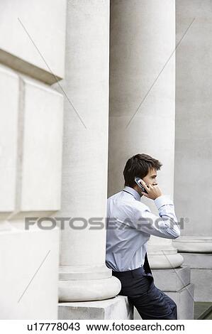 Businessman on cell phone outside building sitting on pillar View Large Photo Image Stock Image - Businessman on cell phone outside building sitting on pillar. Fotosearch
